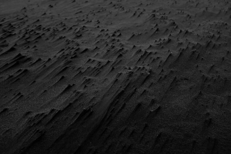 Traits - a black and white photo of sand and water