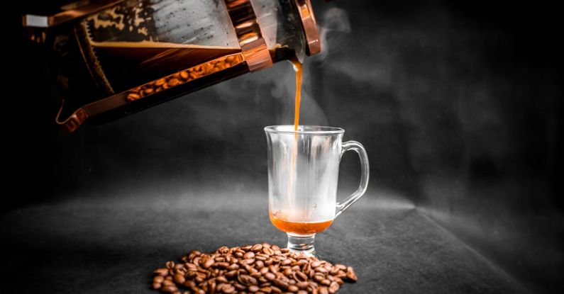 Qualities - Aromatic hot coffee being poured from French press into elegant glass with pile of coffee beans beside on black background