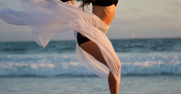 Practices - Skinny dancer jumping over sandy shore of ocean